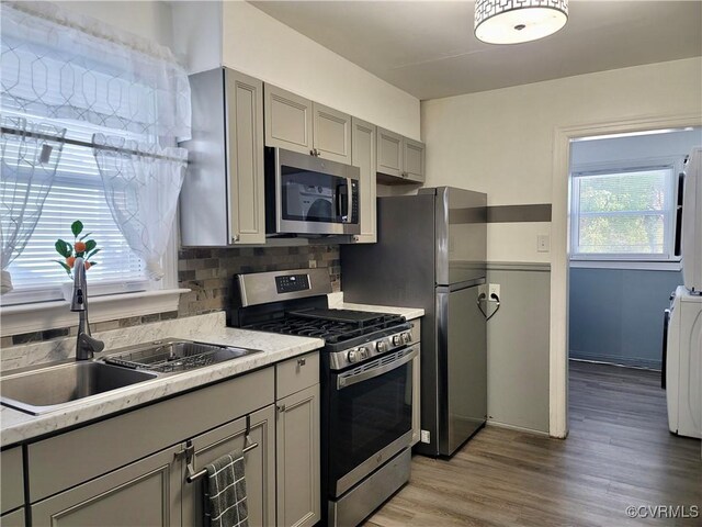 kitchen featuring gray cabinets, appliances with stainless steel finishes, washer / clothes dryer, sink, and backsplash