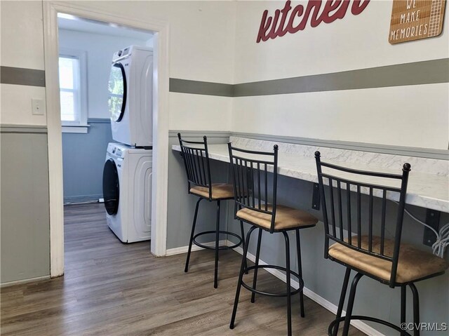 interior space with stacked washer and clothes dryer, dark hardwood / wood-style floors, and bar