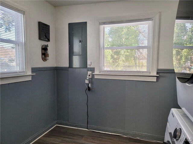 doorway to outside with washer / dryer, dark hardwood / wood-style floors, electric panel, and a wealth of natural light