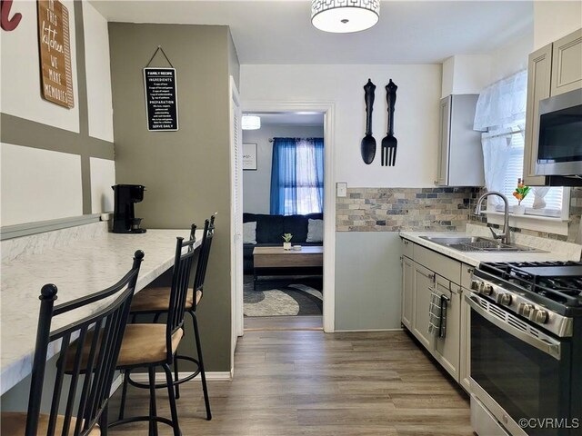 kitchen with stainless steel appliances, sink, gray cabinetry, and decorative backsplash