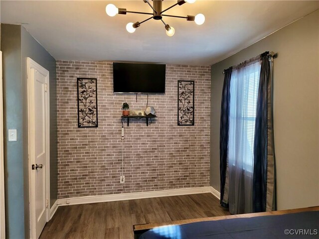 unfurnished bedroom featuring brick wall and dark hardwood / wood-style flooring