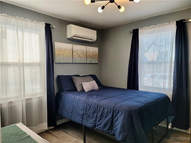 bedroom with hardwood / wood-style floors and a wall unit AC