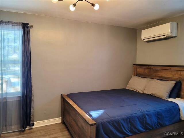 bedroom with wood-type flooring and an AC wall unit