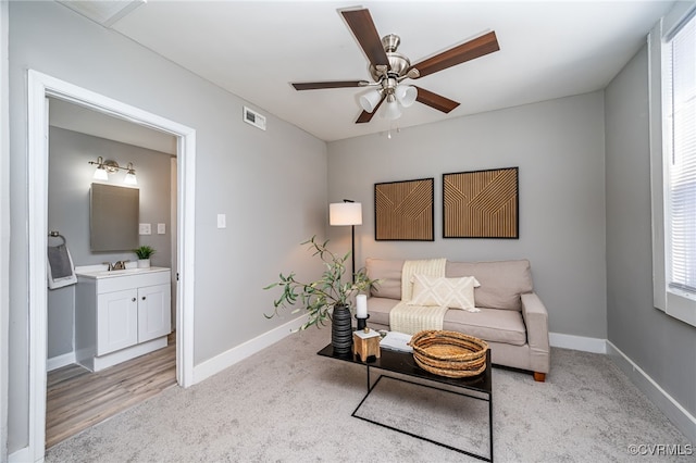 carpeted living room with ceiling fan and sink