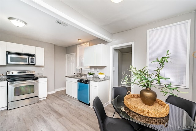 kitchen featuring sink, light hardwood / wood-style flooring, appliances with stainless steel finishes, white cabinetry, and light stone countertops