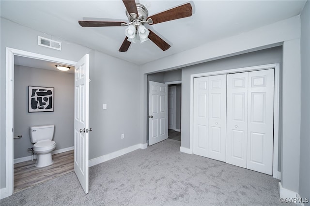 unfurnished bedroom with light colored carpet, a closet, ceiling fan, and ensuite bathroom