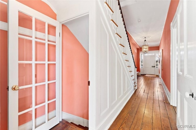 hall with hardwood / wood-style floors and an inviting chandelier