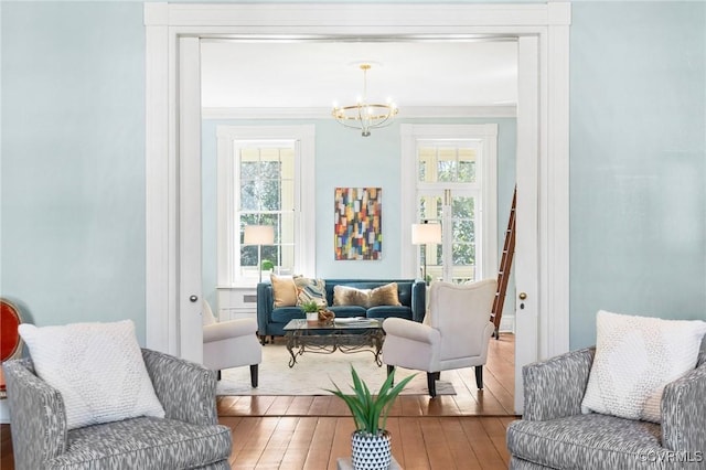 sitting room featuring ornamental molding, wood-type flooring, and a notable chandelier