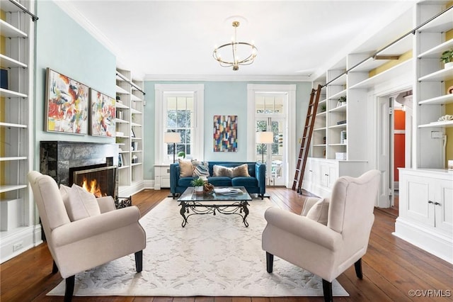 sitting room featuring crown molding, a chandelier, built in features, a fireplace, and hardwood / wood-style floors