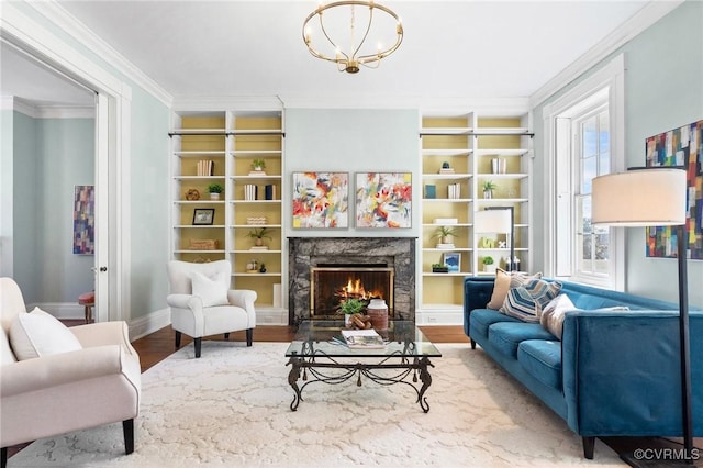 sitting room with hardwood / wood-style floors, built in features, a high end fireplace, crown molding, and an inviting chandelier