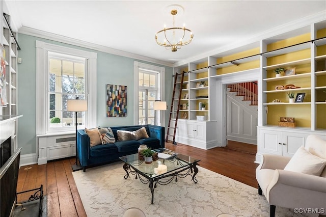 sitting room featuring dark wood-type flooring, an inviting chandelier, crown molding, and built in shelves