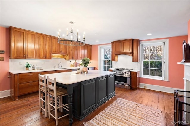 kitchen featuring pendant lighting, dark wood-type flooring, a breakfast bar, high end stainless steel range oven, and a kitchen island