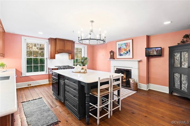 kitchen featuring tasteful backsplash, wood-type flooring, a chandelier, a kitchen island, and pendant lighting