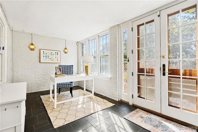 doorway with french doors, a healthy amount of sunlight, and brick wall