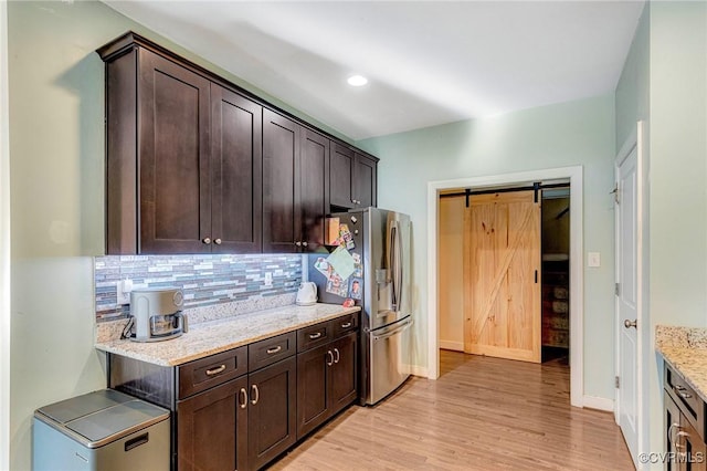 kitchen with a barn door, dark brown cabinets, and stainless steel fridge with ice dispenser