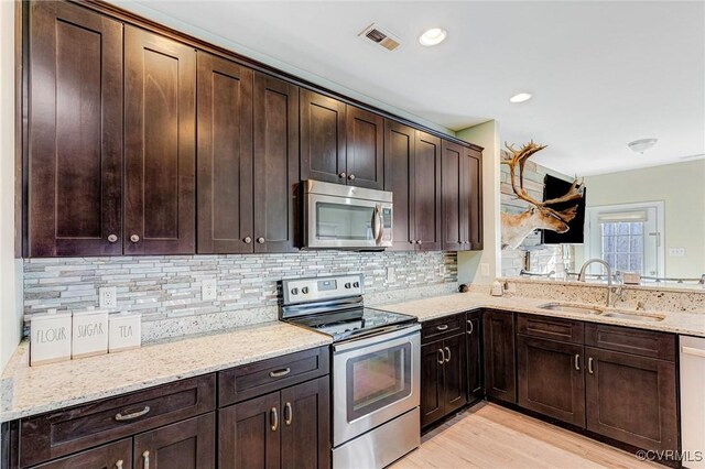 kitchen with sink, dark brown cabinetry, light stone counters, stainless steel appliances, and light hardwood / wood-style flooring