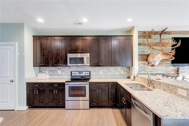 kitchen featuring stainless steel appliances, light stone countertops, sink, and light hardwood / wood-style flooring