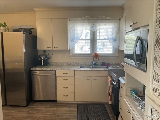 kitchen featuring appliances with stainless steel finishes, sink, white cabinets, ornamental molding, and dark wood-type flooring