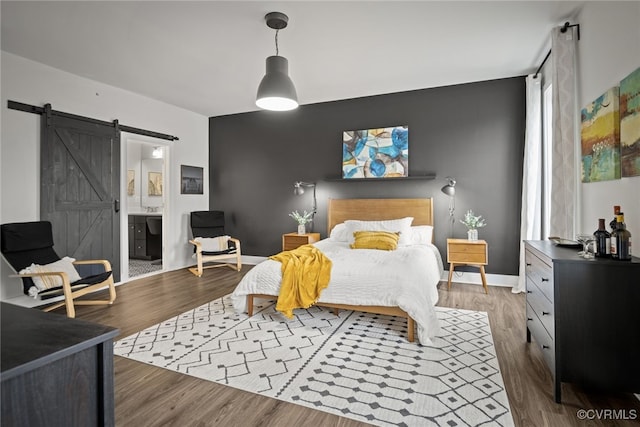 bedroom featuring dark hardwood / wood-style floors, connected bathroom, and a barn door