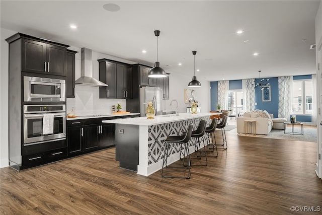 2616 Lassen Walk Unit B, Henrico, VA 23294 - kitchen featuring a kitchen island with sink, wall chimney exhaust hood, light countertops, open floor plan, and appliances with stainless steel finishes