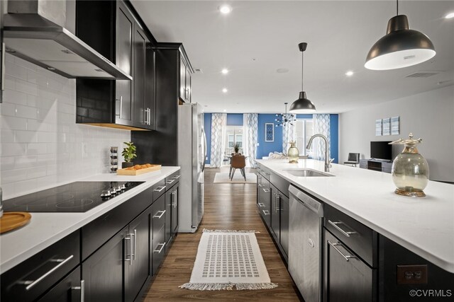 kitchen with pendant lighting, wall chimney range hood, stainless steel appliances, and sink