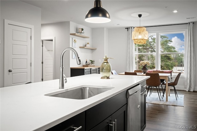 kitchen featuring stainless steel dishwasher, sink, pendant lighting, and dark wood-type flooring