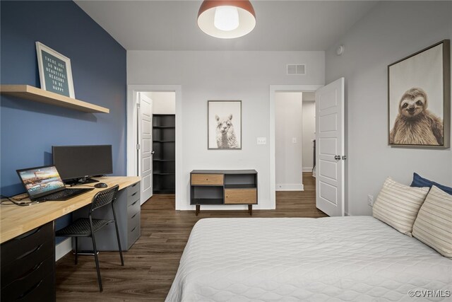 bedroom featuring a spacious closet and dark hardwood / wood-style floors