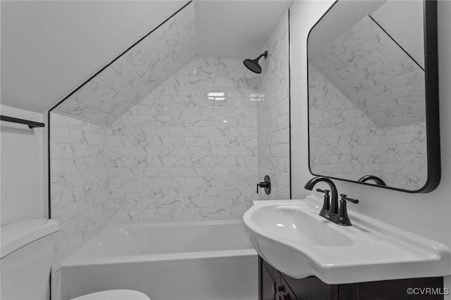 full bathroom featuring vanity, tiled shower / bath, vaulted ceiling, and toilet