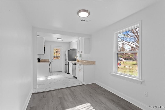 kitchen featuring white cabinetry, stainless steel appliances, and light wood-type flooring