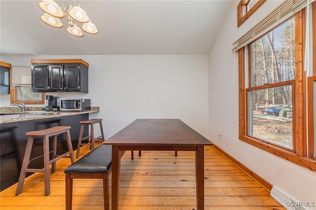 dining space featuring vaulted ceiling, sink, a chandelier, and light wood-type flooring