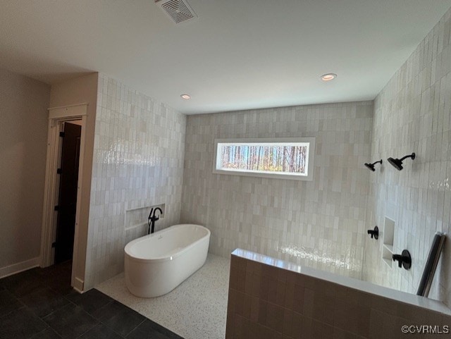 full bath featuring tile walls, a walk in shower, tile patterned floors, visible vents, and a freestanding bath