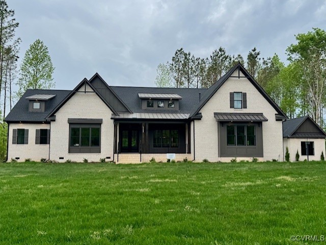 rear view of house featuring metal roof, a standing seam roof, and a yard