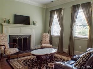 living area featuring hardwood / wood-style flooring and crown molding