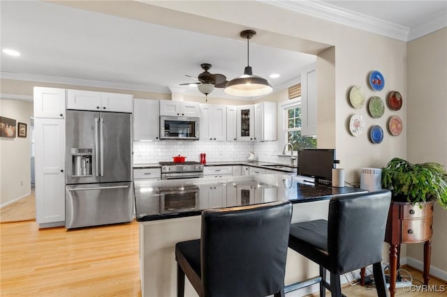 kitchen with white cabinetry, a breakfast bar area, premium appliances, and kitchen peninsula