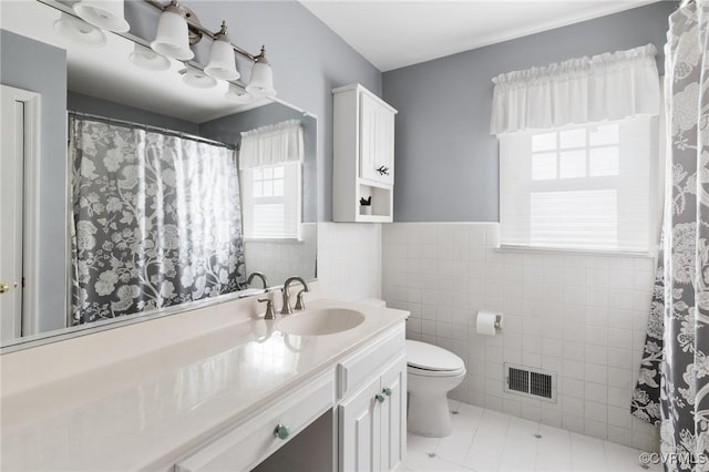 bathroom with tile patterned flooring, vanity, tile walls, and toilet