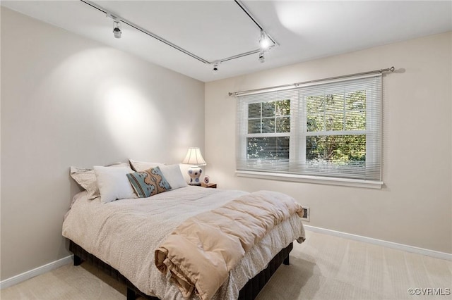 carpeted bedroom featuring track lighting