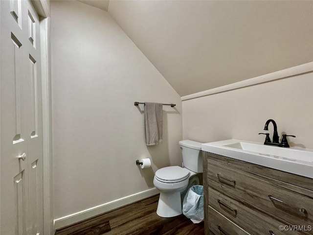 bathroom featuring hardwood / wood-style flooring, vanity, toilet, and vaulted ceiling