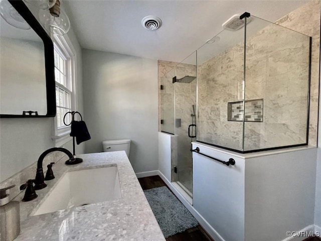 bathroom featuring vanity, toilet, and a shower with door