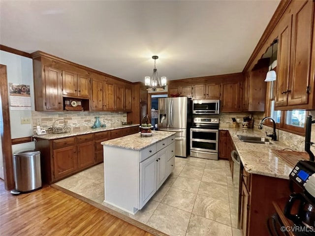 kitchen featuring sink, decorative light fixtures, light stone countertops, and appliances with stainless steel finishes