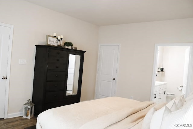 bedroom with dark wood-type flooring and connected bathroom