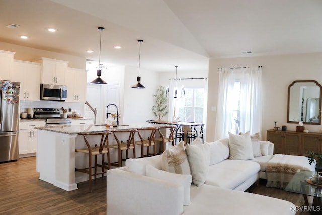 living room featuring sink, a notable chandelier, dark wood-type flooring, and vaulted ceiling