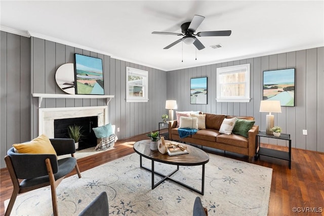 living room featuring ornamental molding, dark wood-type flooring, ceiling fan, and a high end fireplace