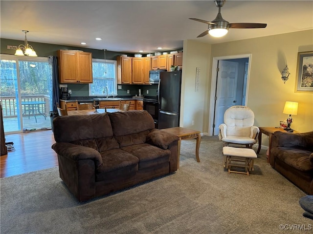 living room with light carpet, sink, and a healthy amount of sunlight