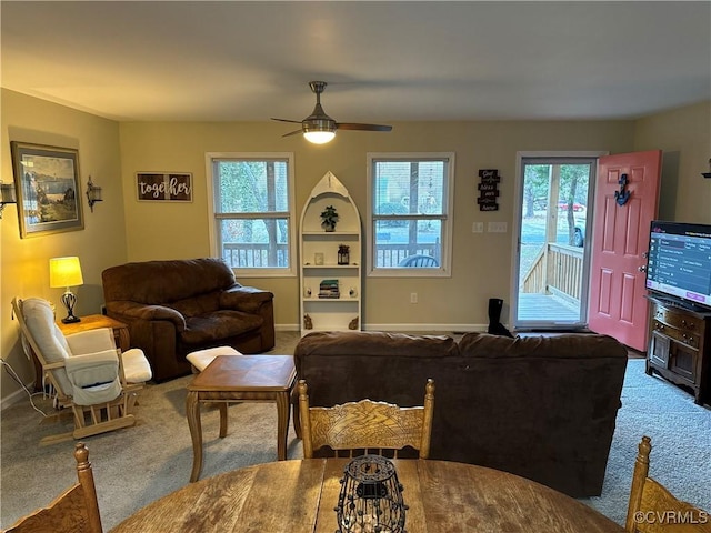 carpeted living room featuring built in shelves and ceiling fan