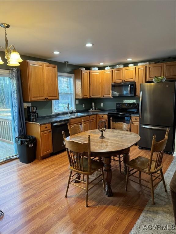 kitchen with decorative light fixtures, black appliances, and light hardwood / wood-style floors