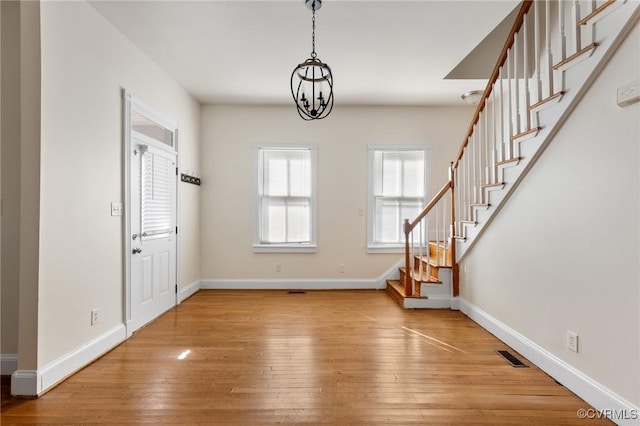 foyer entrance with light hardwood / wood-style flooring and a chandelier