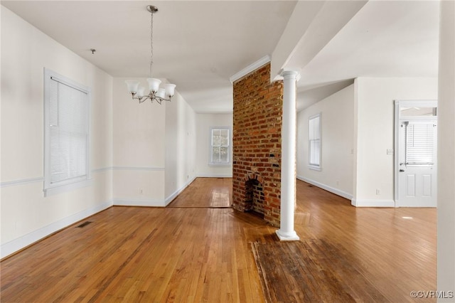 unfurnished dining area with wood-type flooring, decorative columns, and a chandelier