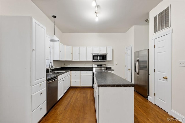 kitchen with a kitchen island, white cabinetry, sink, hanging light fixtures, and stainless steel appliances