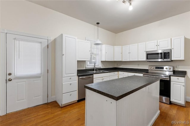 kitchen featuring sink, appliances with stainless steel finishes, white cabinetry, hanging light fixtures, and a kitchen island