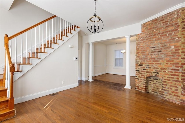 unfurnished living room with decorative columns, hardwood / wood-style floors, and a chandelier